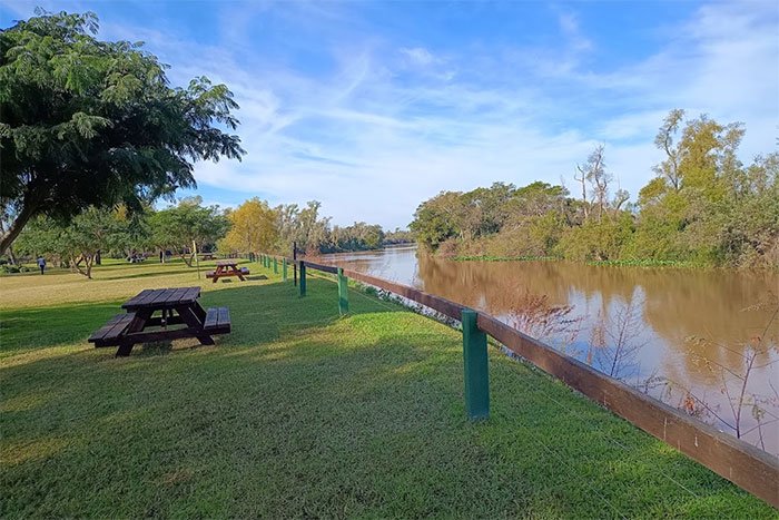 Parque con mesas y árboles a orillas de un riacho, camping del Parque Nacional Pre-Delta