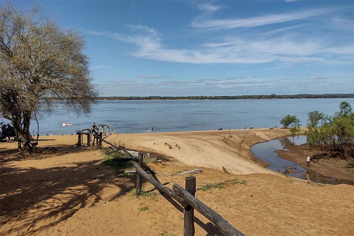 Costa de arena sobre el río Uruguay con baranda de troncos, Parque Nacional El Palmar