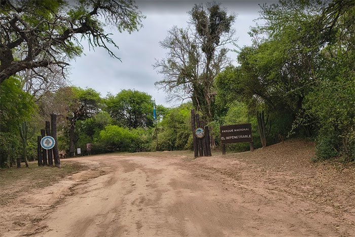 Camino de tierra y cartel de ingreso al Parque Nacional El Impenetrable, en el monte chaqueño